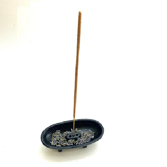 Incense stick in a small black dish with incense crystals on a white background