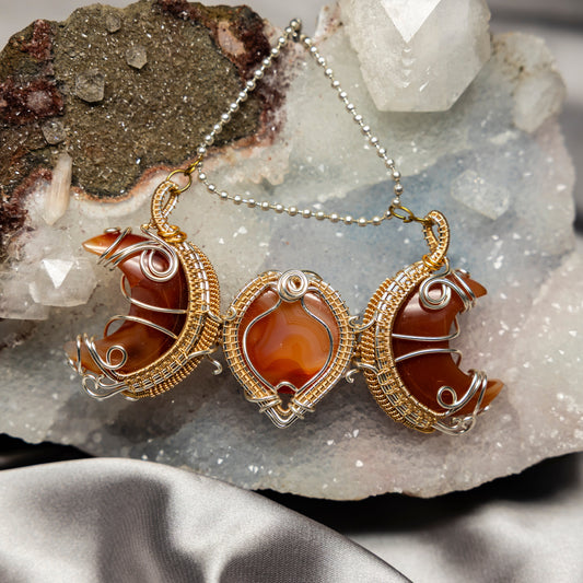 Ornate necklace with orange carnelian agate stones on a crystal background