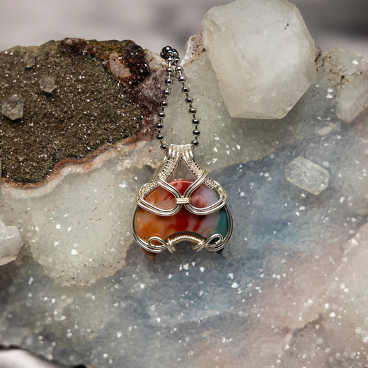 Necklace with a colorful chakra agate pendant on a crystal background
