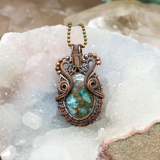 Decorative pendant with a chrysocolla crystal on a textured surface