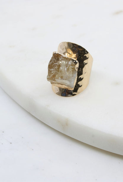 Gold ring with a rough-cut gemstone on a white surface