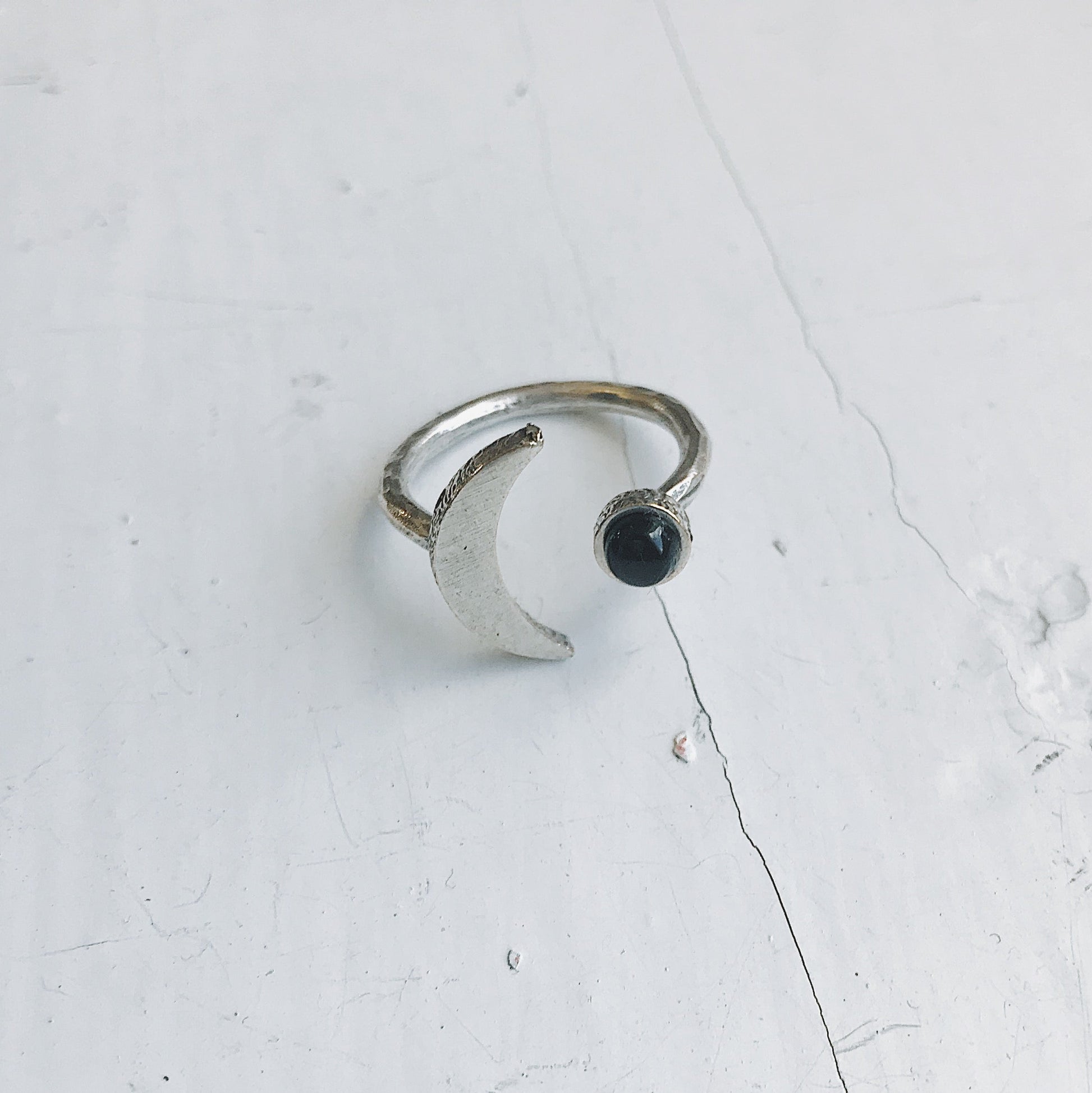 Silver ring with a black onyx gemstone on a light gray background