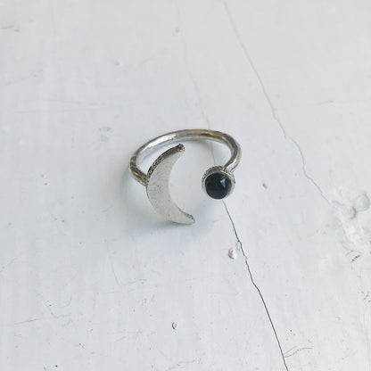 Silver ring with a black onyx gemstone on a light gray background