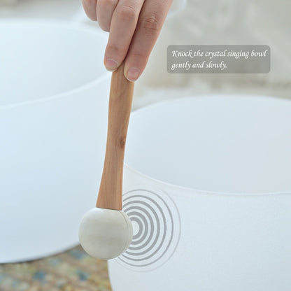 Crystal singing bowl with a wooden mallet and text instruction on a blurred background