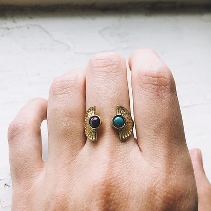 Gold ring with gemstones on a hand against a neutral background