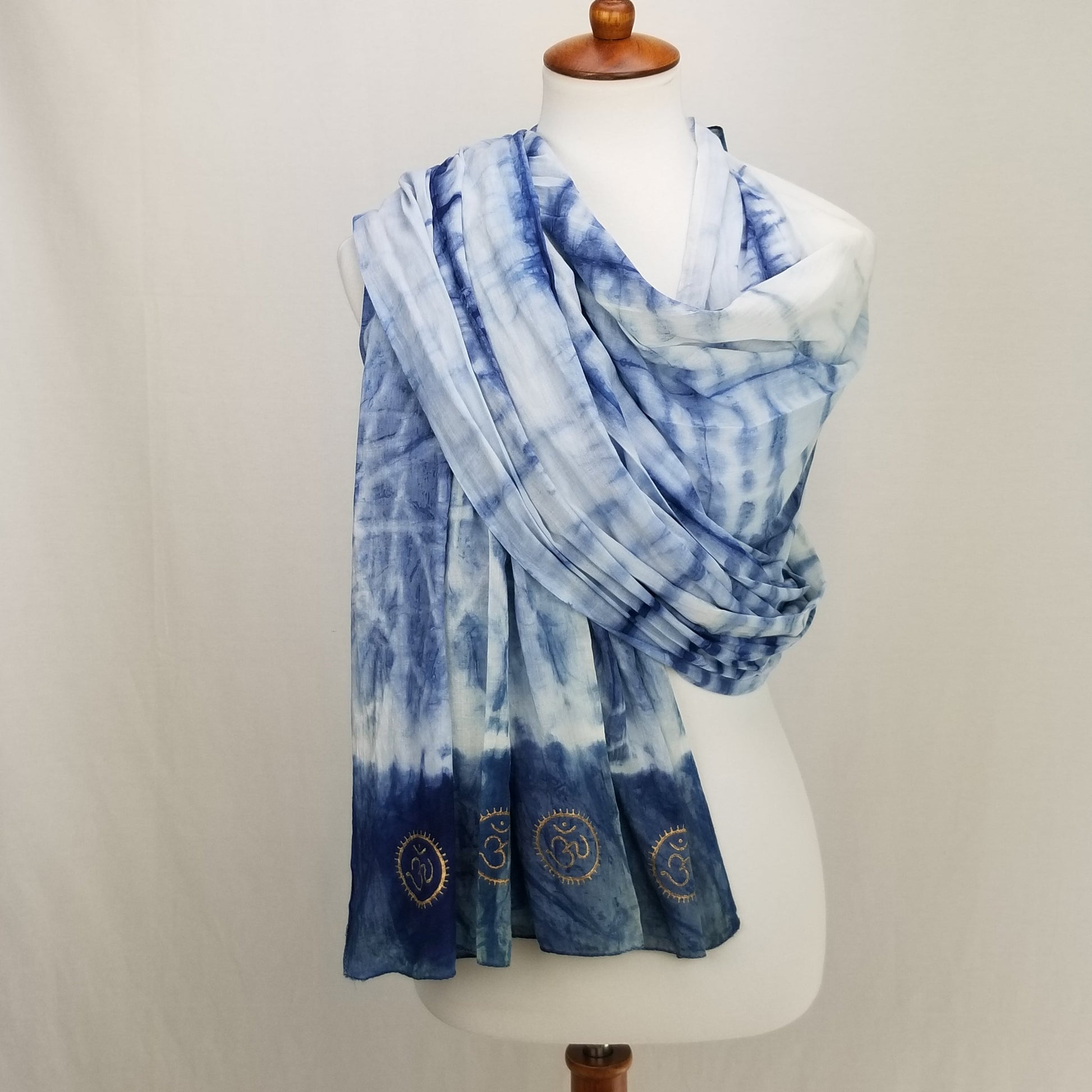 Blue tie-dye scarf with embroidered designs on a mannequin against a white background