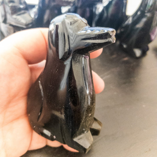 Hand holding a shiny black dog figurine with blurred background