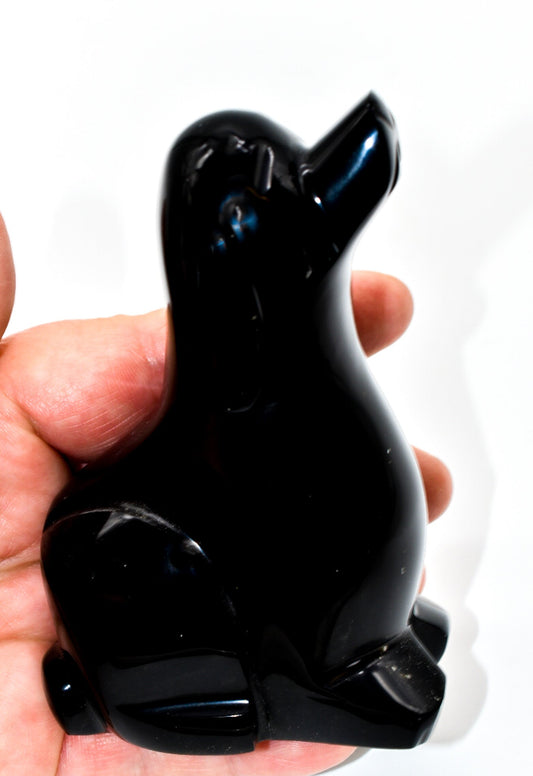 Black obsidian dog-shaped object held in a hand against a white background