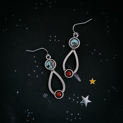 Silver earrings with gemstones on a starry night background