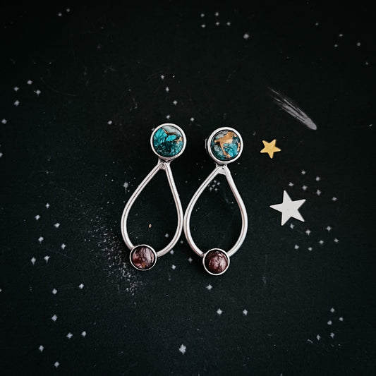 Pair of earrings with gemstones on a black background with star decorations