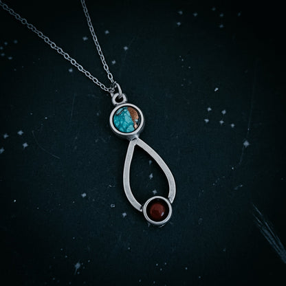 Silver necklace with a pendant featuring turquoise and red stones on a dark background