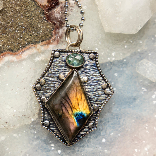 Necklace with a pendant featuring a colorful labradorite stone on a textured surface