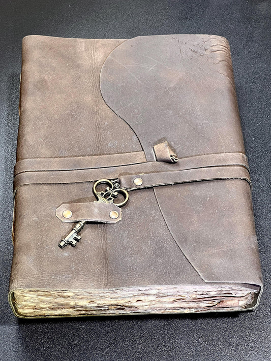 Brown leather-bound book with decorative key locks on a dark background