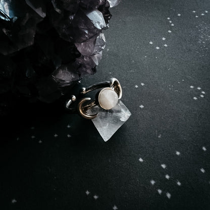 Ring with a central moonstone gemstone on a dark surface