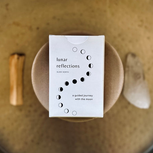 Box labeled 'lunar reflections' on a textured surface with natural elements.