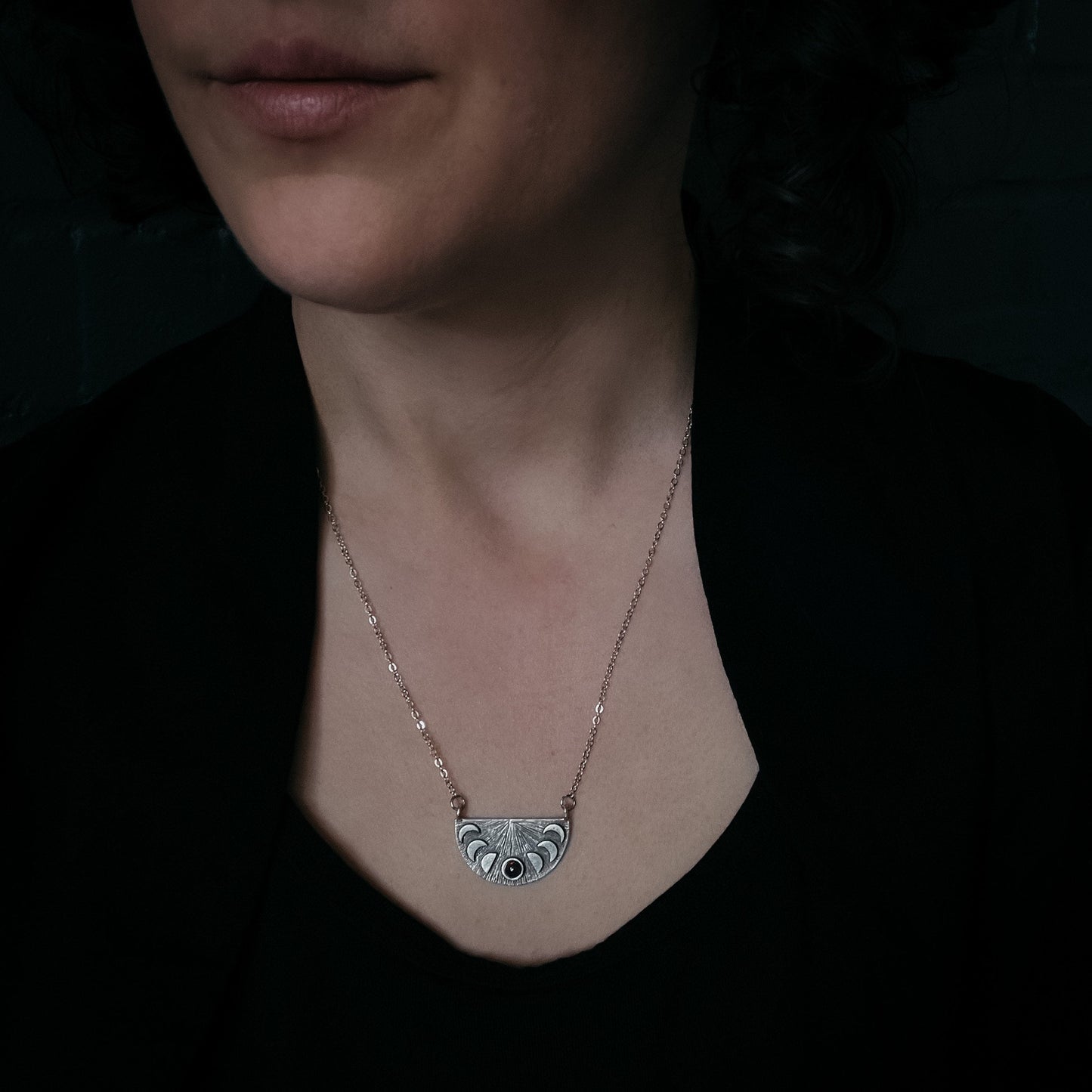 Necklace with a decorative pendant worn by a woman against a dark background