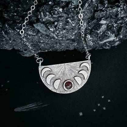 Silver necklace with a half-circle pendant on a dark background