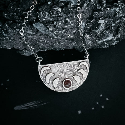 Silver necklace with a half-circle pendant on a dark background