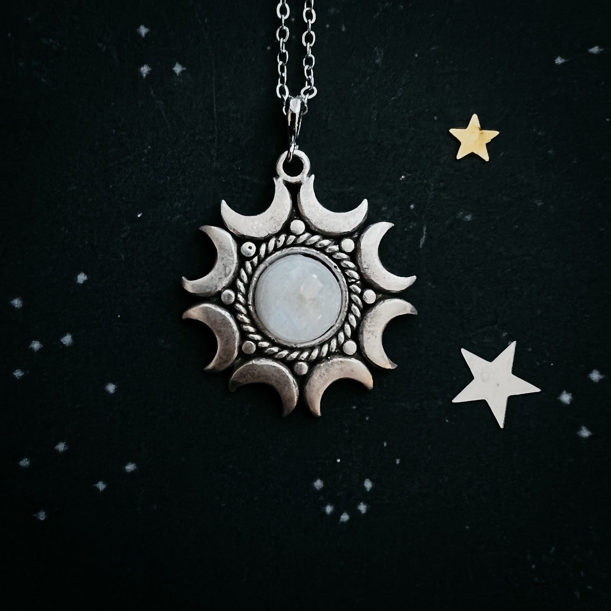 Moonstone pendant necklace on a black background with stars.