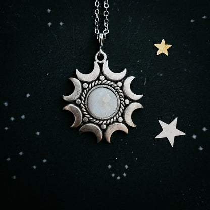 Moonstone pendant necklace on a black background with stars.
