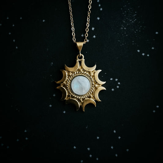 Gold pendant with a moonstone on a dark background
