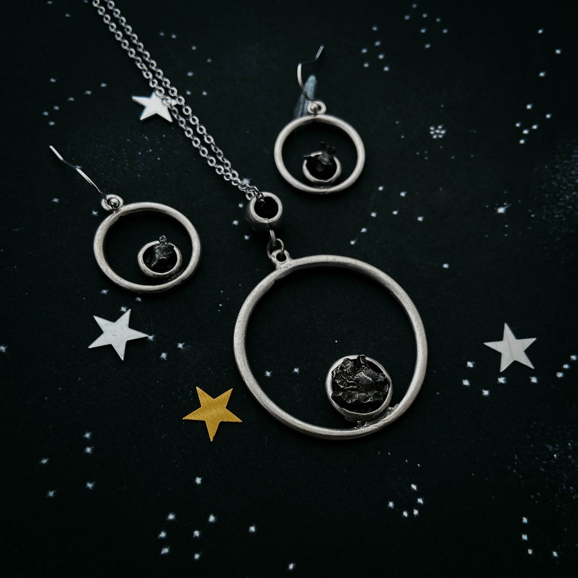Silver jewelry set with circular designs on a starry background