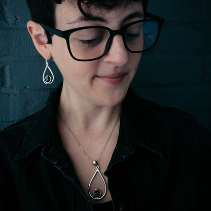 Woman wearing black glasses and a black shirt with a dark background