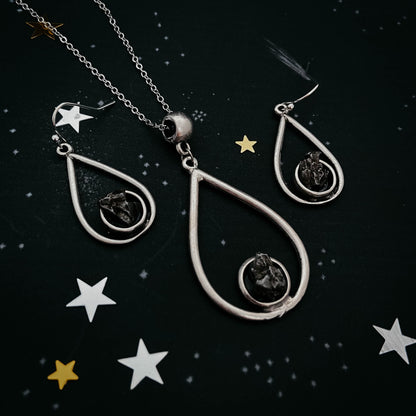 Silver teardrop-shaped jewelry set with star decorations on a dark background