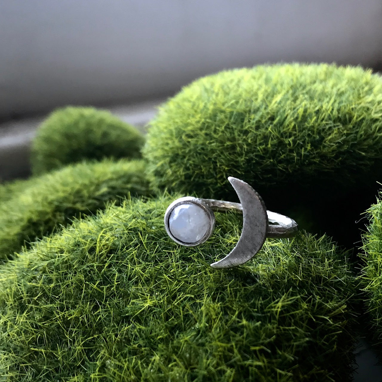 Silver ring with a moon design on a green textured surface