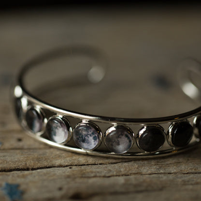 Silver bracelet with embedded stones on a wooden surface