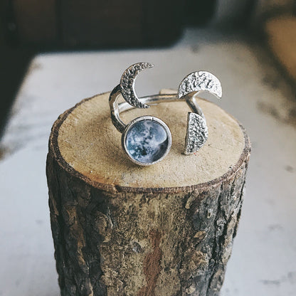 Silver tone ring with moon design on a wooden block