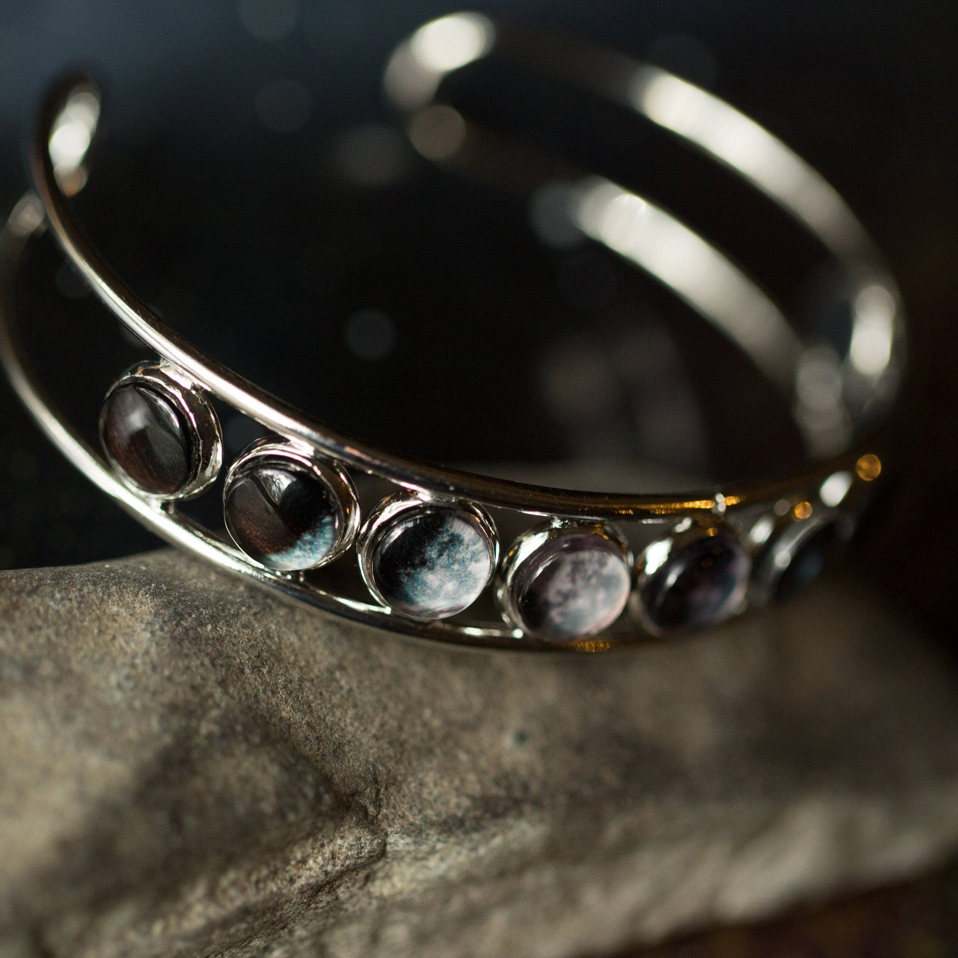 Silver adjustable cuff bracelet with embedded stones on a dark background