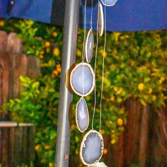 Decorative hanging wind chime with agate stones against a blurred garden background