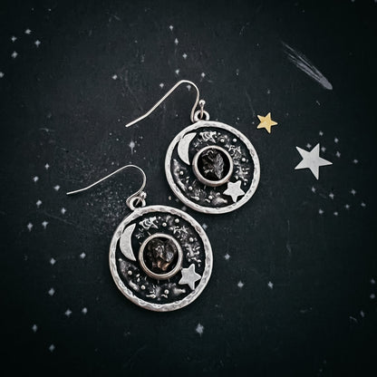 Silver earrings with celestial design on a dark background