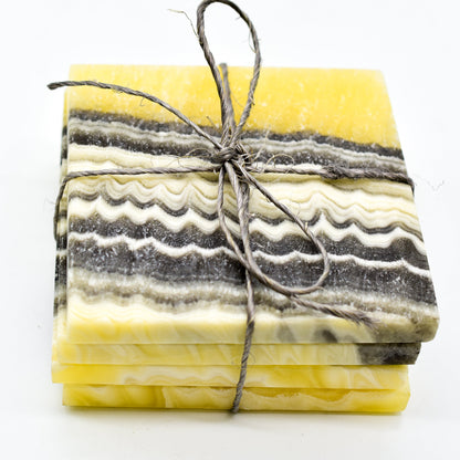 Stack of marbled yellow and gray coasters tied with twine on a white background