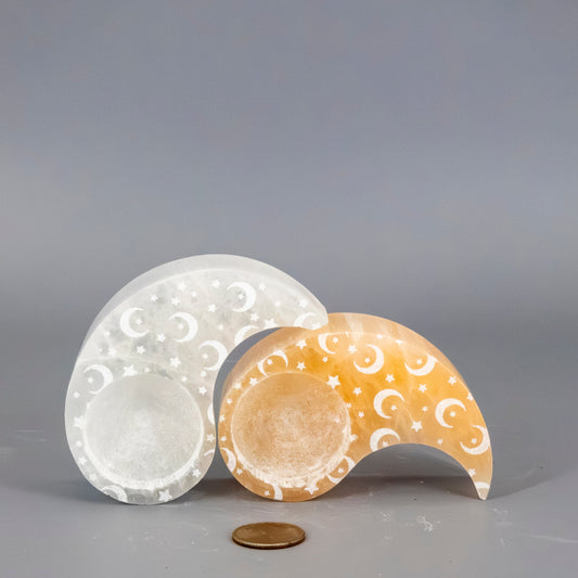 Two decorative selenite tea light candles with intricate patterns on a gray background