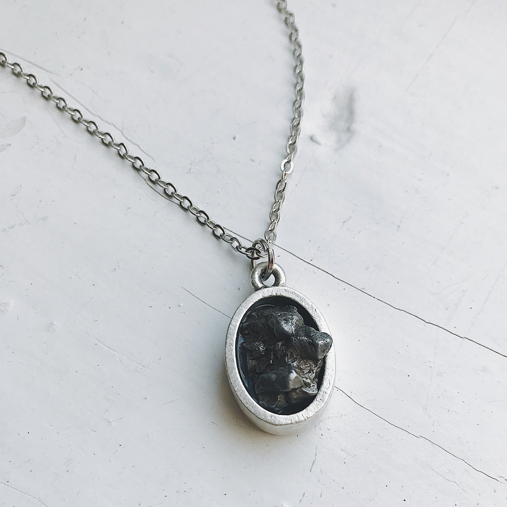 Necklace with a pendant featuring meteorite on a light gray background