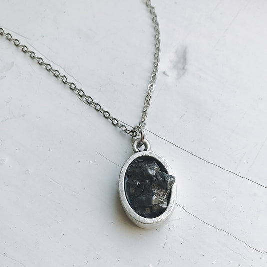 Necklace with a pendant featuring meteorite on a light gray background