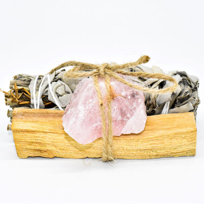 Sage bundle, rose quartz crystal, and wooden box on a white background