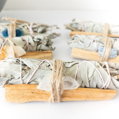 Three bundles of sage smudge sticks on a white surface
