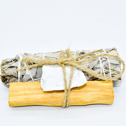 Sage bundle tied with twine, palo santo and a crystal on a white background