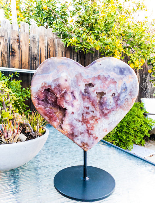 Heart-shaped geode on a stand outdoors with greenery in the background