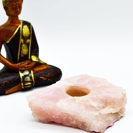 Pink stone candle holder with a small Buddha statue on a white background