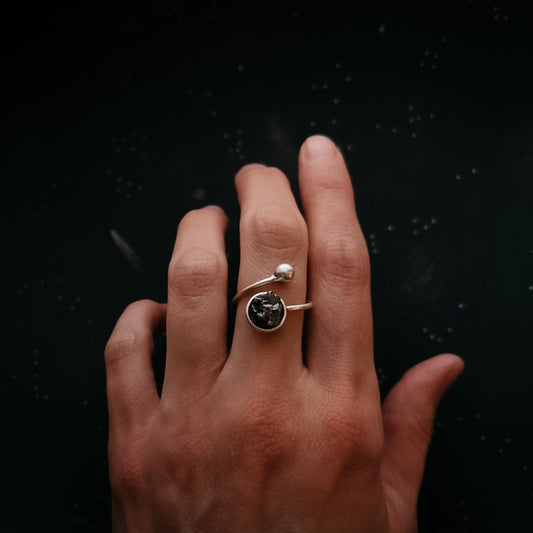 Hand wearing a ring with meteorite on a black background