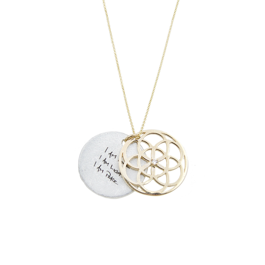 Necklace with a gold circular seed of life pendant and a white disc with text on a white background
