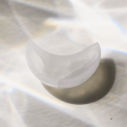 Selenite crescent moon-shaped bowl on a reflective surface