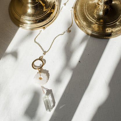 Gold necklace with crystal pendant on a white surface