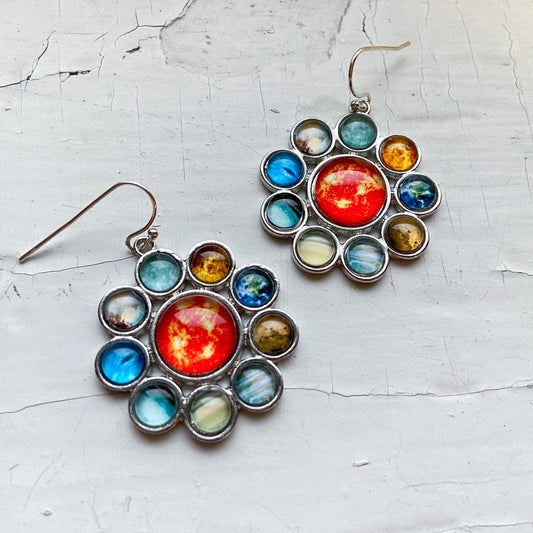 Colorful celestial-themed earrings on a textured white surface