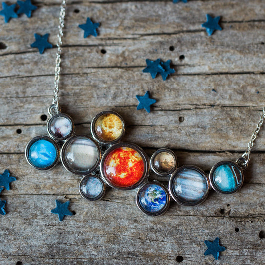 Necklace with planet-shaped pendants on a wooden surface with star decorations