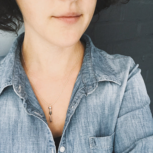 Wiman wearing a necklace with a small pendant containing meteorite dust against a dark background